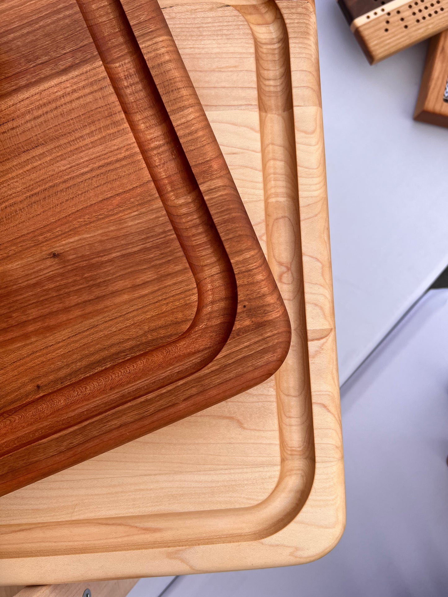 Corners of a naturally light and a naturally dark wooden butcher block cutting board with juice groove cutout on the edge