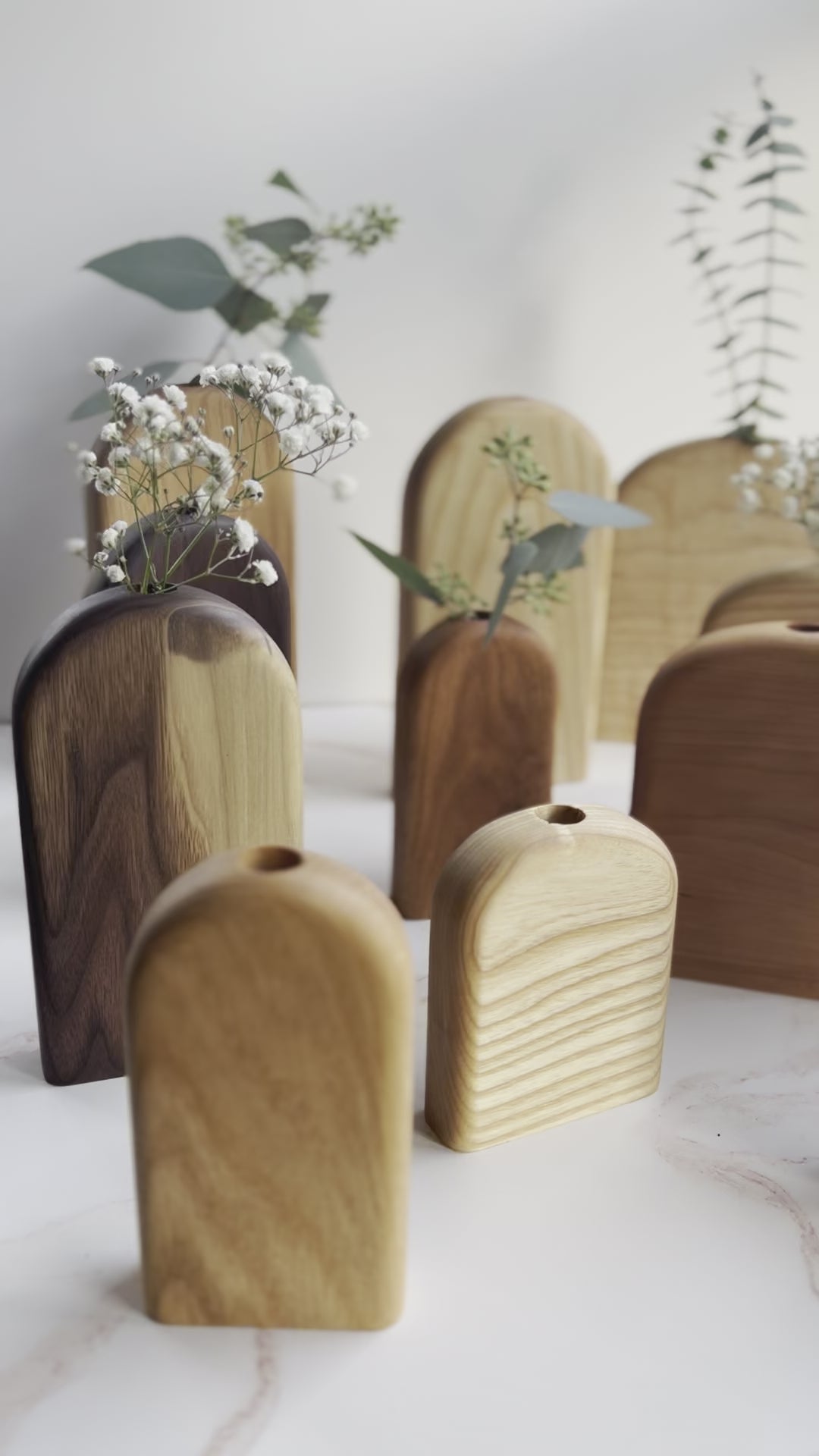 Video of a large collection of rounded top and rectangle organic bud/flower vases in all different variations of light and dark wood handmade by Camino Woodshop in Milwaukee WI, making the perfect decor for your home or gift for friends and family