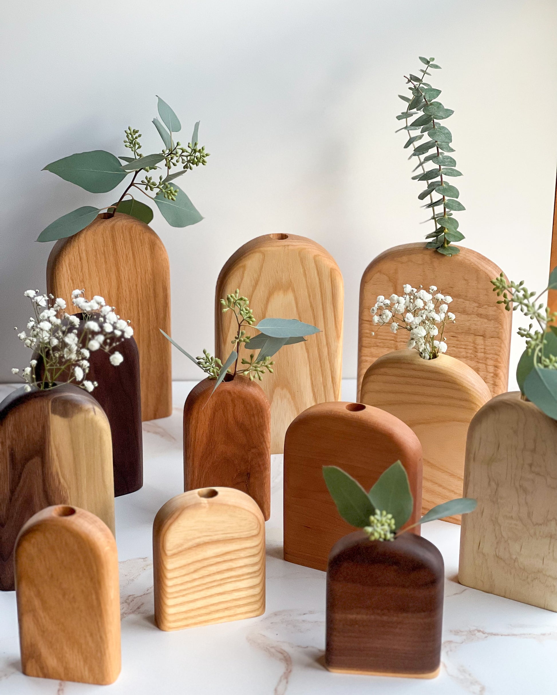 Organic bud/flower vases in all different variations of light and dark wood handmade by Camino Woodshop, making the perfect decor for your home or gift for friends and family