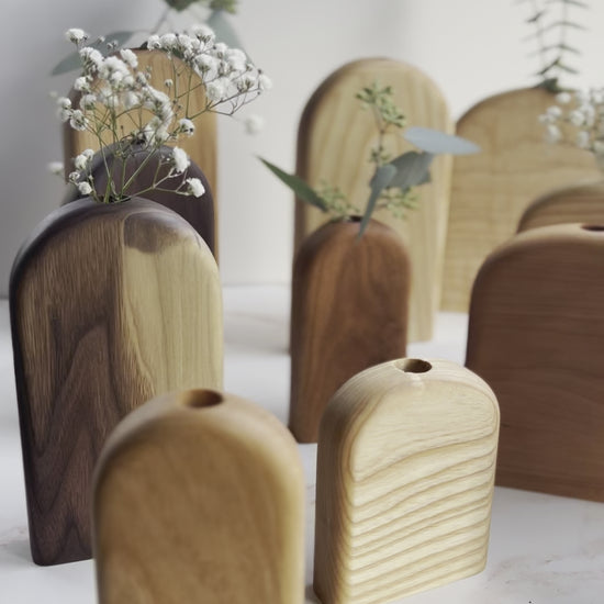 Video of a large collection of rounded top and rectangle organic bud/flower vases in all different variations of light and dark wood handmade by Camino Woodshop in Milwaukee WI, making the perfect decor for your home or gift for friends and family
