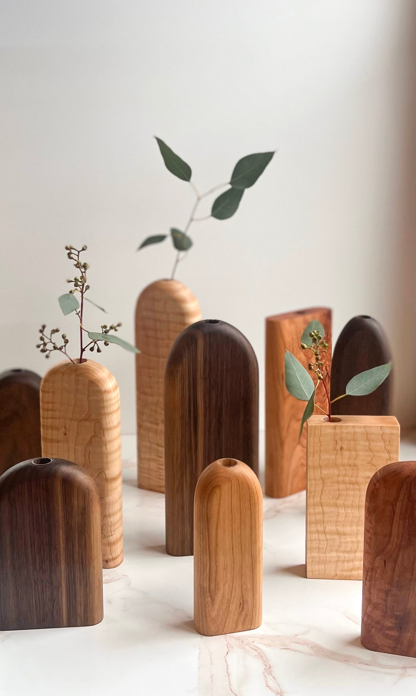 Rounded top and rectangle organic bud/flower vases in all different variations of light and dark wood handmade by Camino Woodshop, making the perfect decor for your home or gift for friends and family