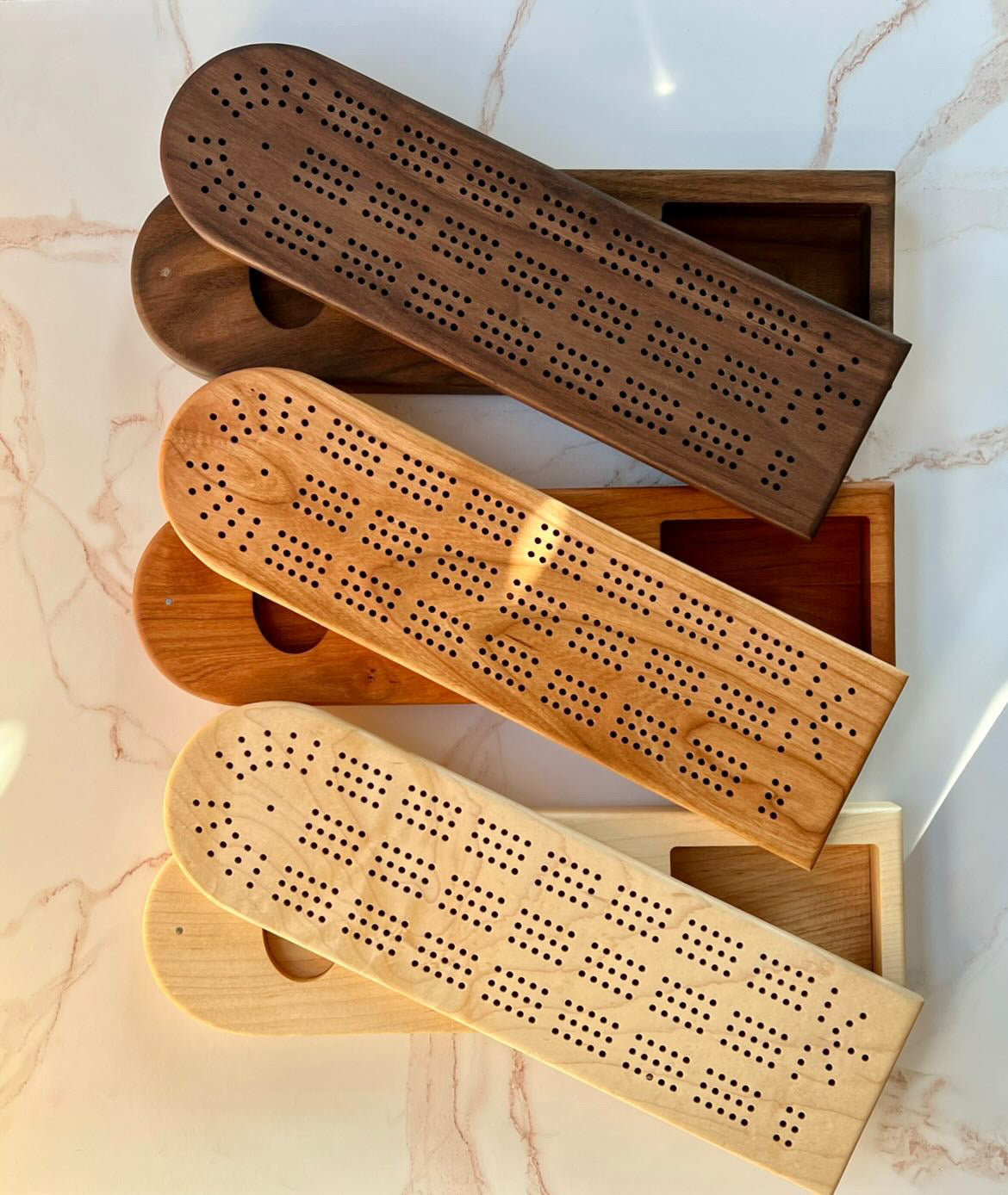 Three handmade wooden cribbage boards with swivel top card and peg storage in 3 different natural wood colors: light, medium and dark, made by Camino Woodshop in Milwaukee, WI makes the perfect Christmas or housewarming gift