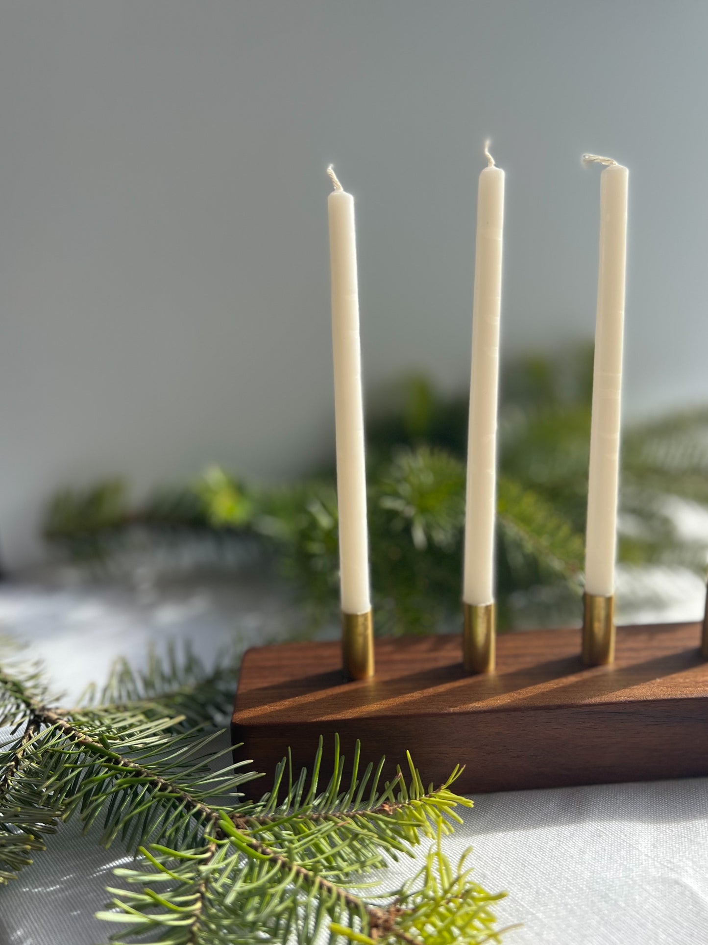 Gorgeous handmade wooden modern looking advent candle holder surrounded by pine needles making the perfect Christmas decoration for your home