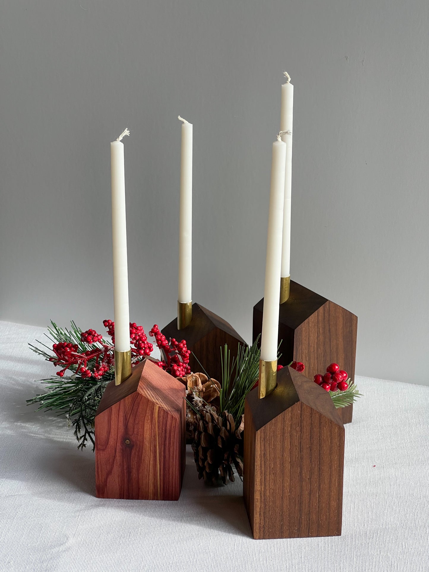 4 beautiful handcrafted wooden modern advent wreath and candle holders surrounded with pinecones and holly, a gorgeous Christmas decoration or gift made by Camino Woodshop in Milwaukee